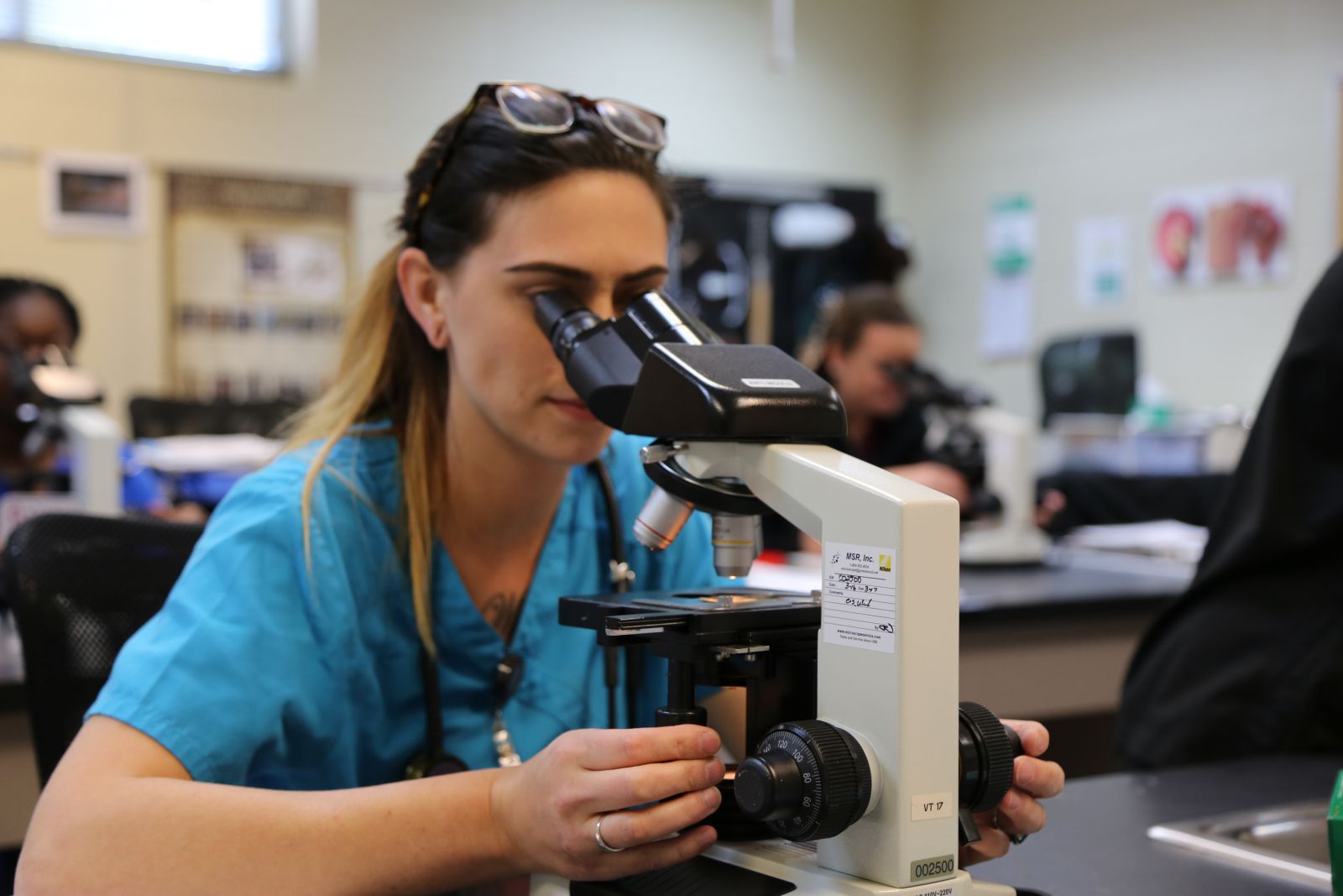 Vet Tech Student Looks through Microscope